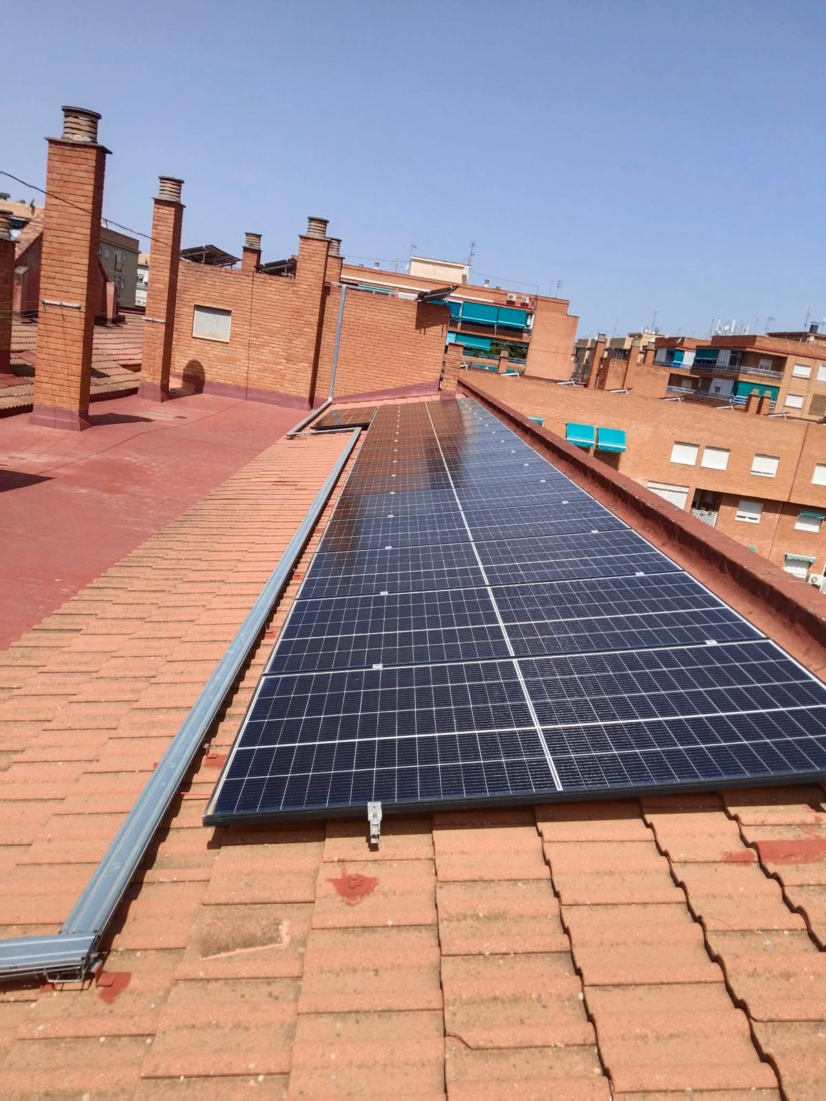 Fila de paneles solares sobre una cubierta de teja junto a una azotea