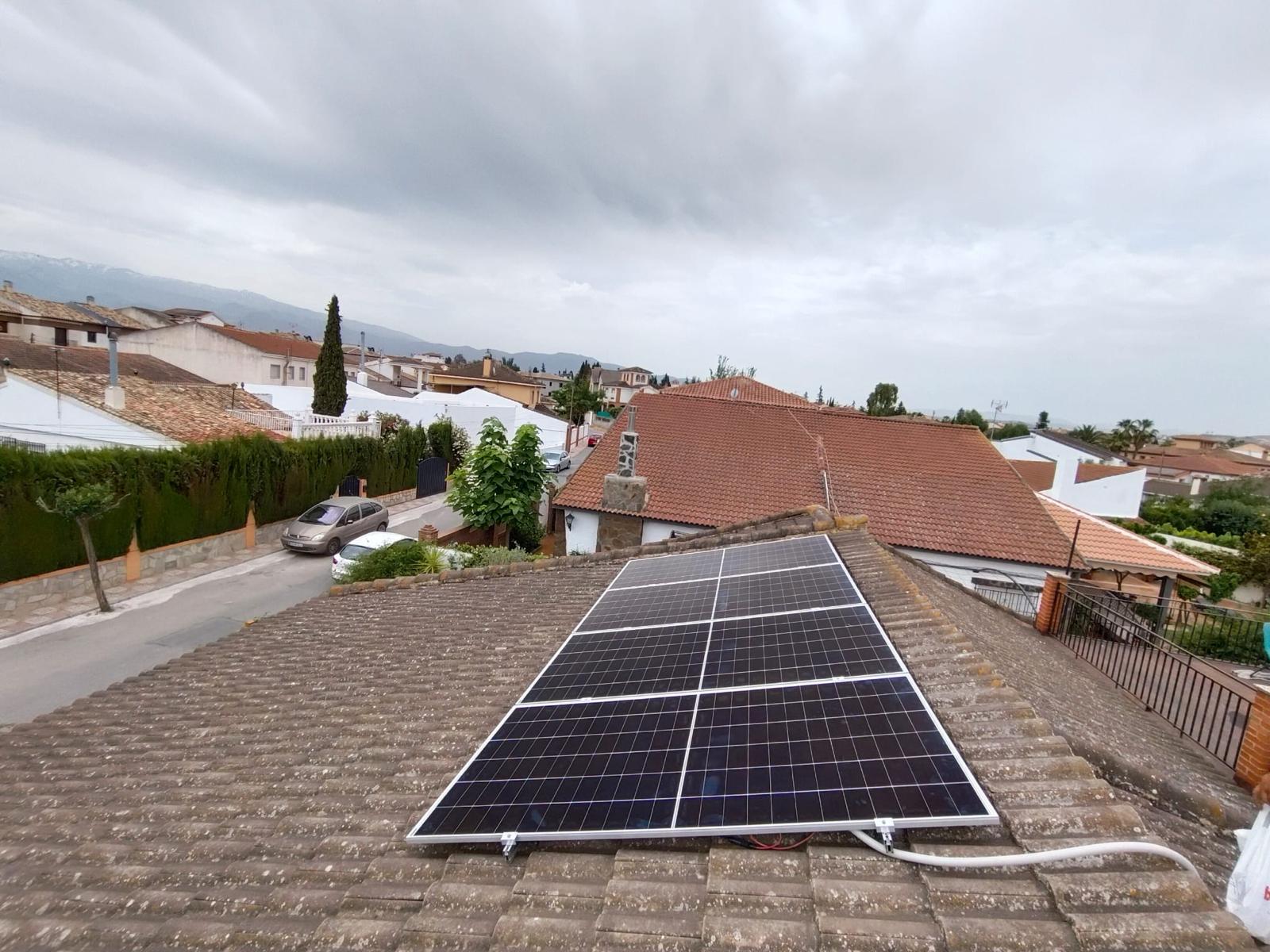 Paneles solares en fila sobre un tejado de teja gris